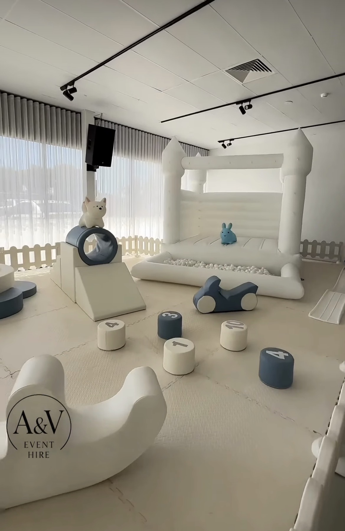 Soft play area with white bouncy castle, rocking toys, and numbered stepping blocks
