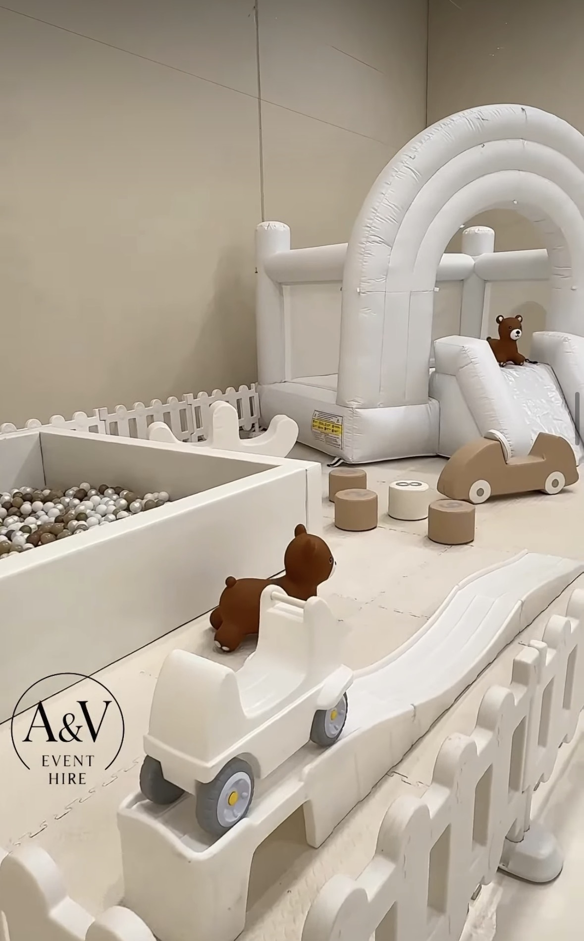 Neutral toned soft play with ball pit, bouncy castle, and ride-on cars